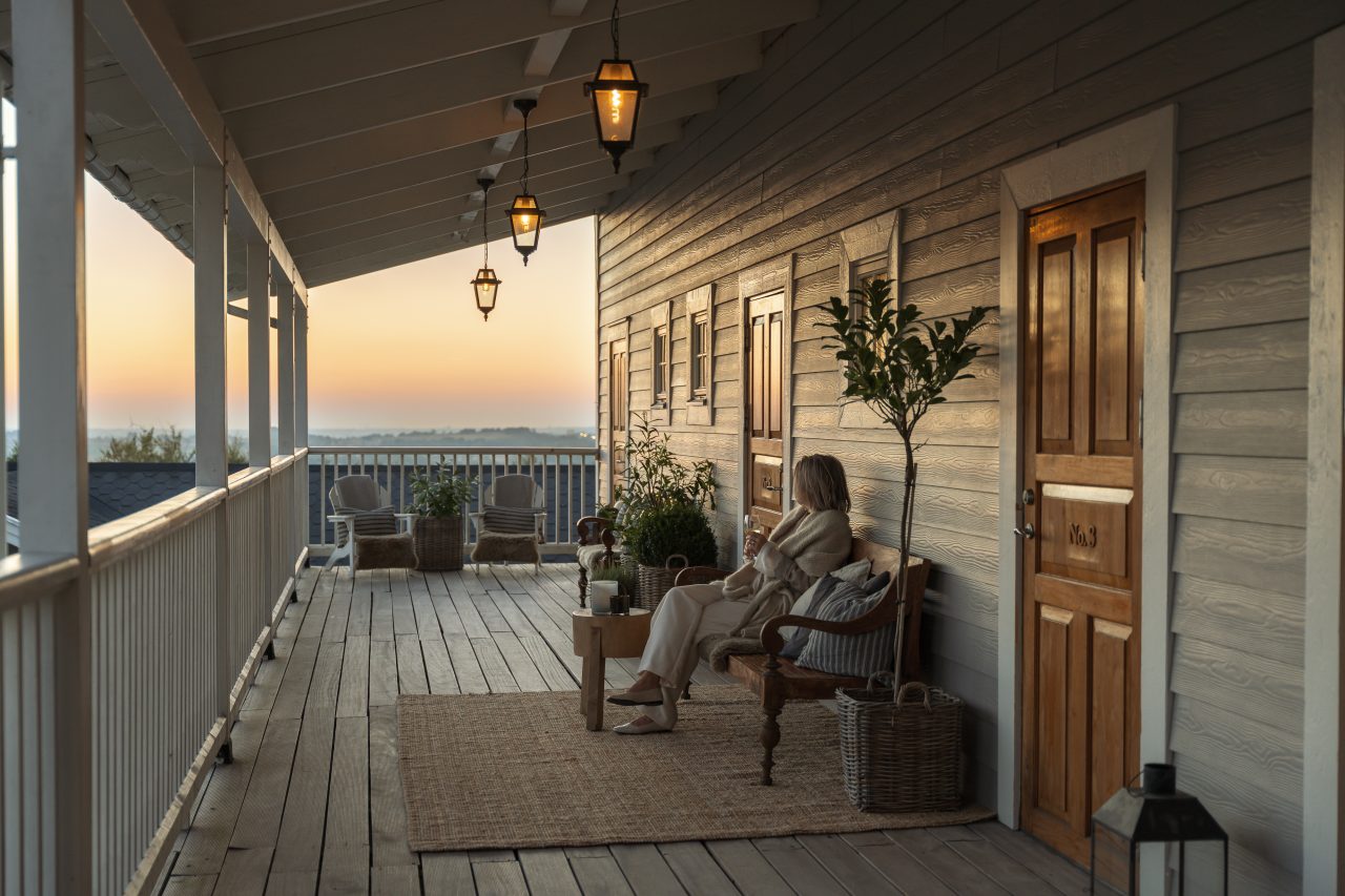 Veranda med lyktor och sittplatser utanför rummen på The Lodge i Skåne