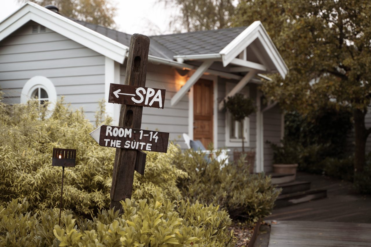 Träskylt visar vägen till Honulele Spa på The Lodge, spahotell i Skåne