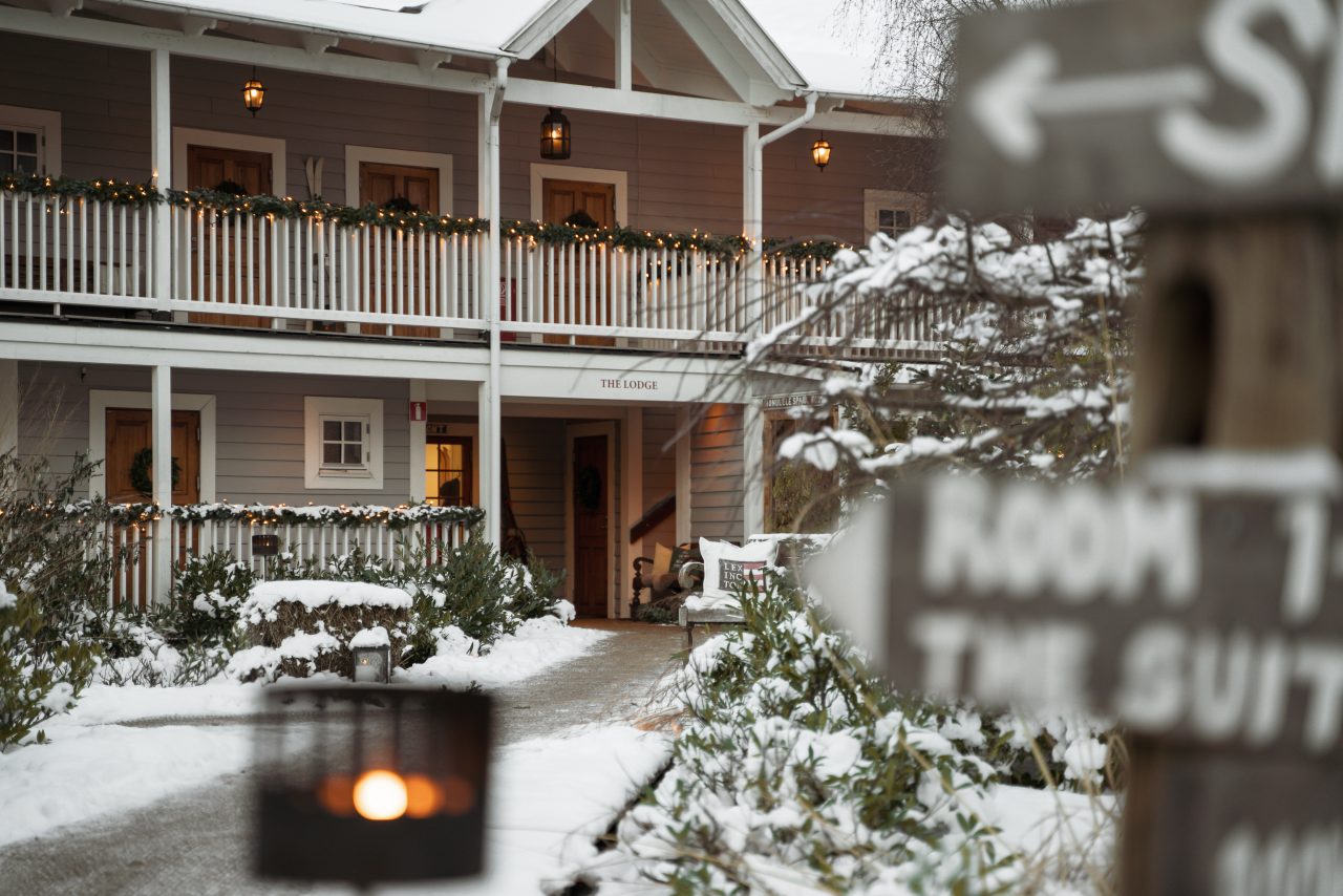 Snöklädd innergård med rumsskyltar och marschall på The Lodge, hotell i Skåne