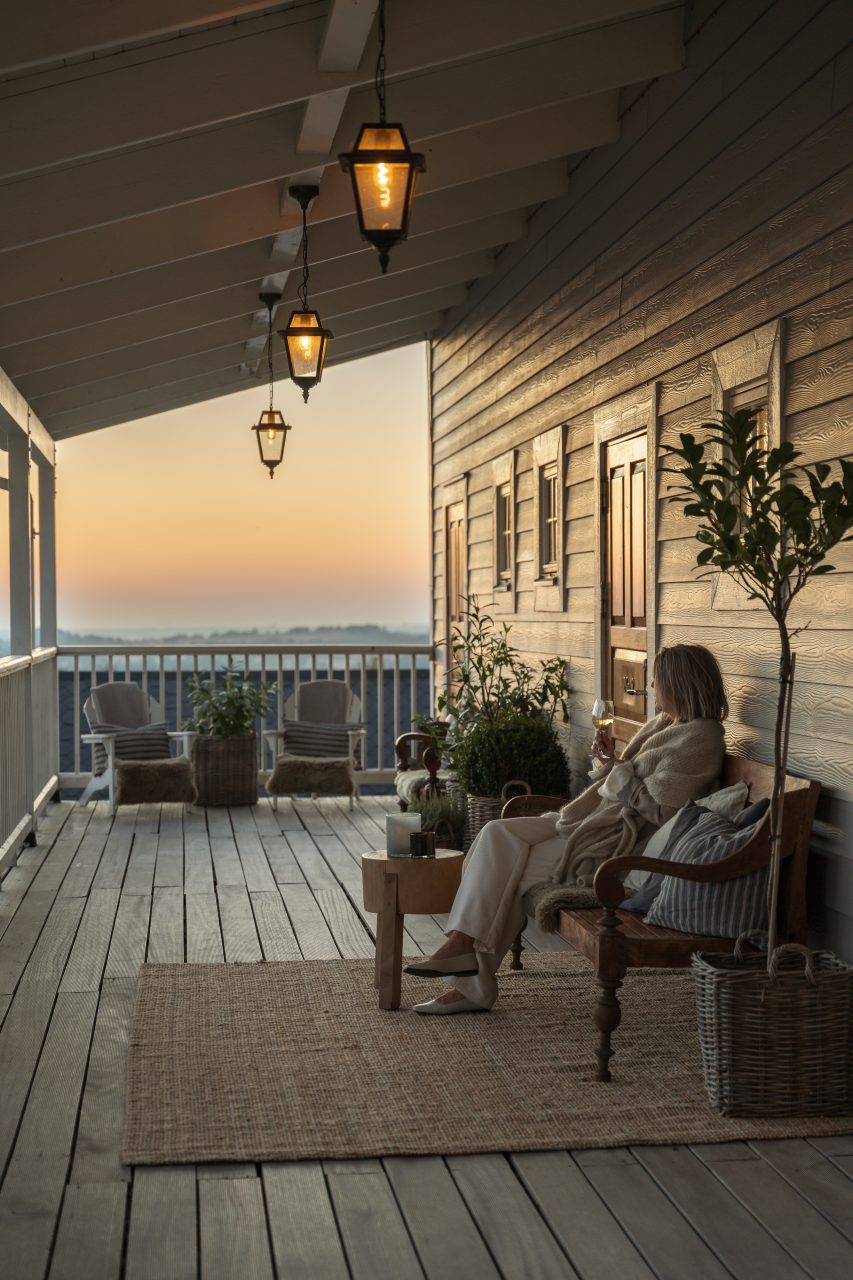 Gäst i fåtölj på verandan i solnedgången på The Lodge, hotell på Romeleåsen i Skåne