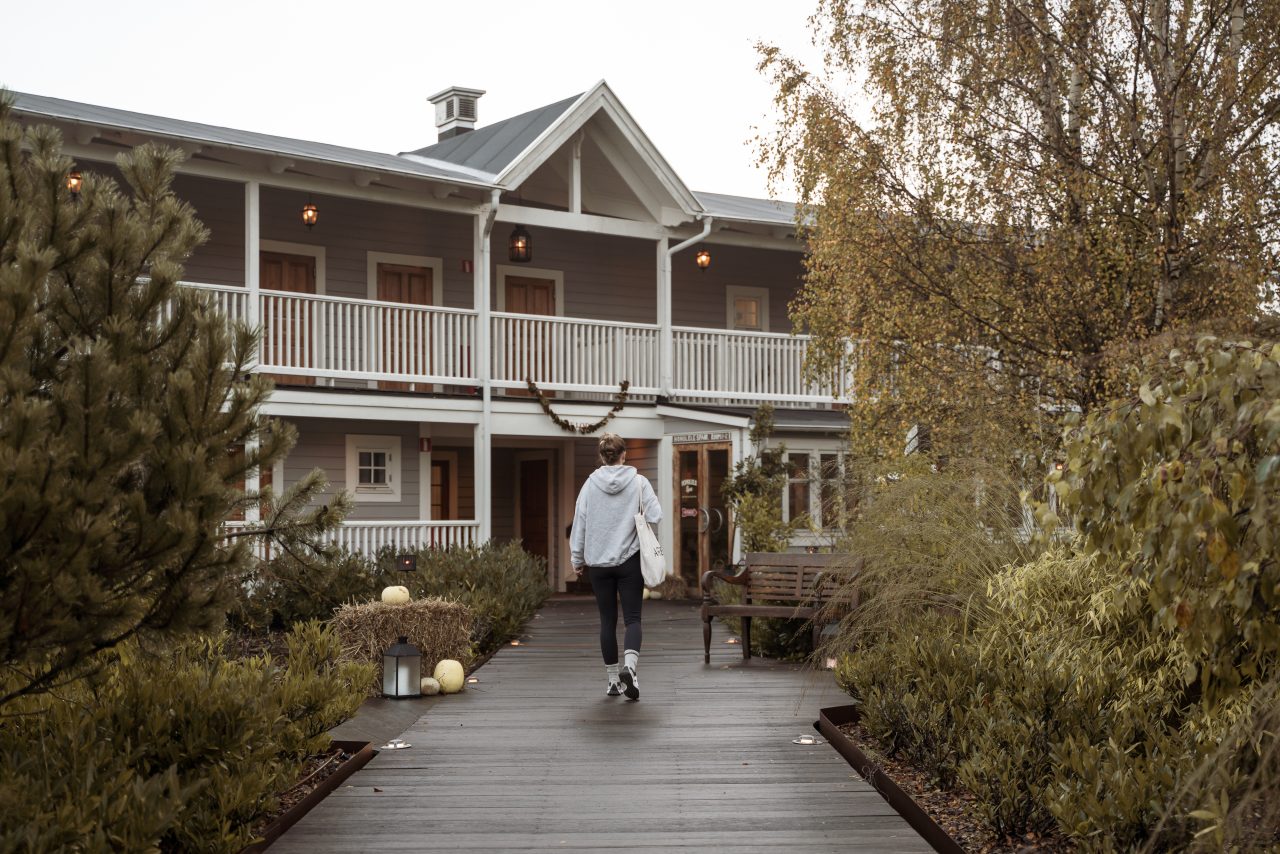 Gäst promenerar på trädäcket mellan husen på The Lodge på Romeleåsen