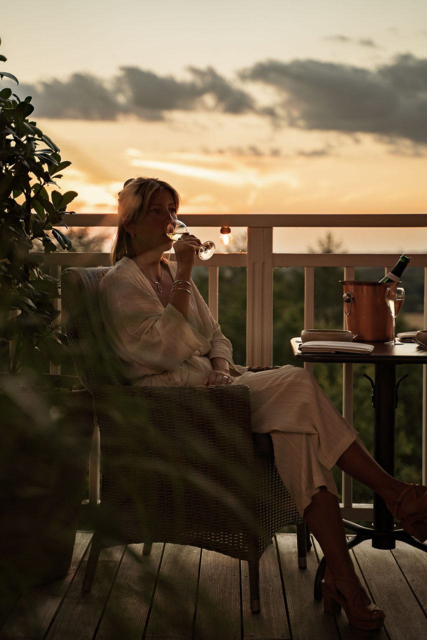 Gäst njuter av solnedgången på verandan på The Lodge