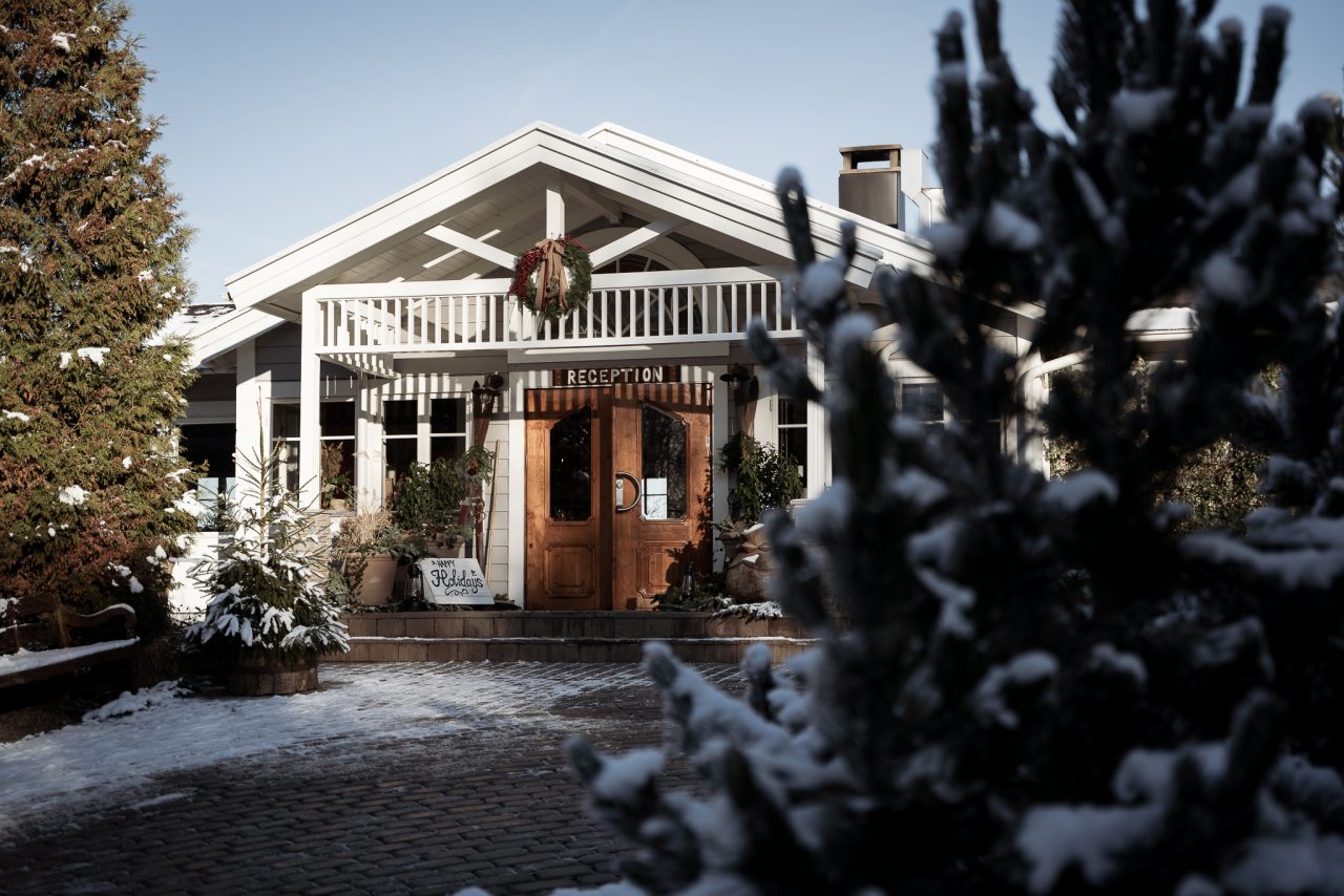 Huvudbyggnaden på The Lodge med julkrans i snön