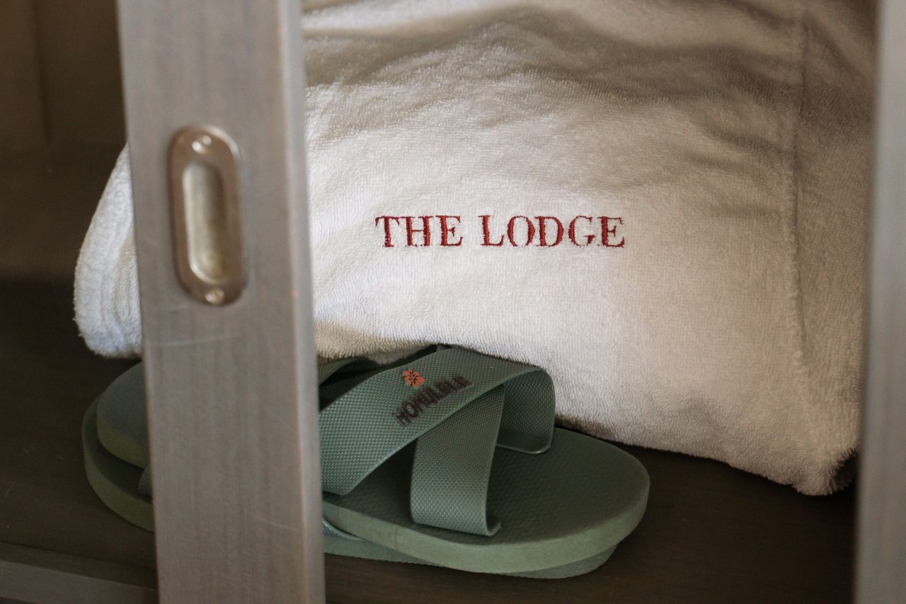 Kudde med The Lodge-logotypen och tofflor