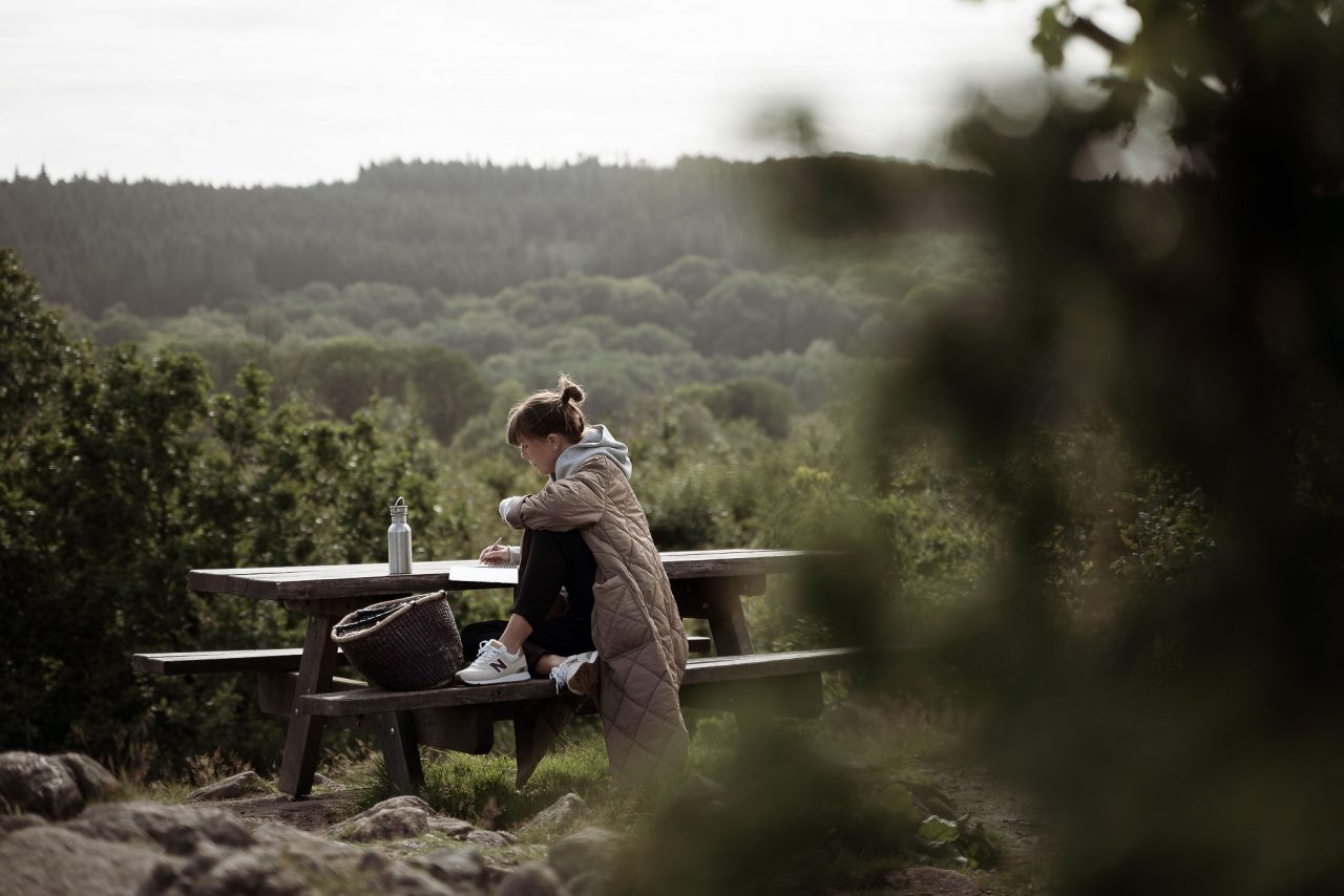 Gäst vid picknickbordet i naturen kring The Lodge